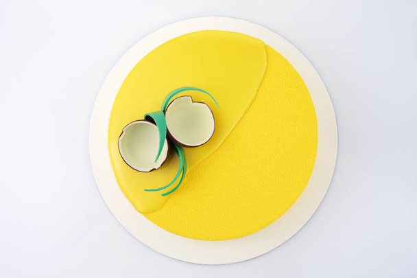 Yellow tropical mousse cake decorated with coconut of chocolate on a white background closeup top view flat lay - Foto, Imagem