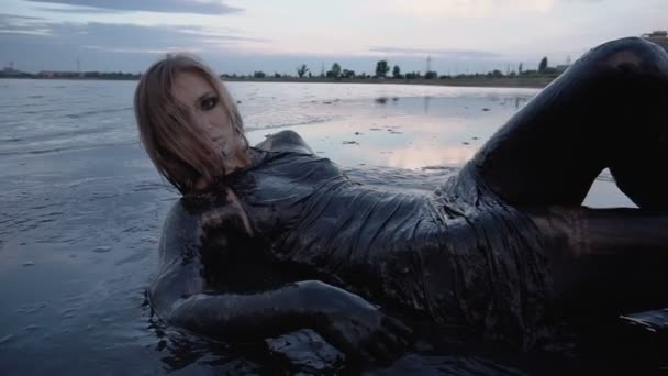Adorable Slender Blonde Lays Smeared in a Black Mud looks like Petroleum Oil - Footage, Video