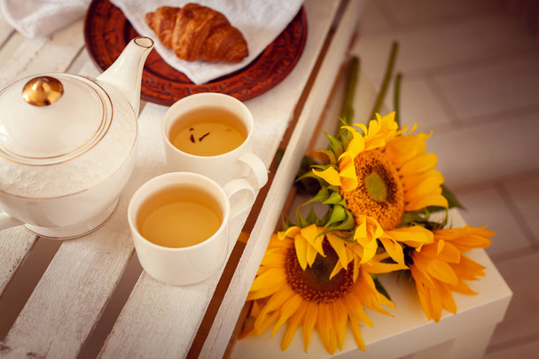 Ένα καλοκαιρινό Ρομαντικό πρωινό για δύο άτομα από το τσάι, κρουασάν και ηλιοτρόπια - Φωτογραφία, εικόνα
