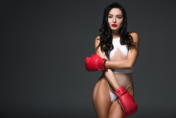 seductive sportive woman in white swimwear and boxing gloves isolated on grey - 写真・画像