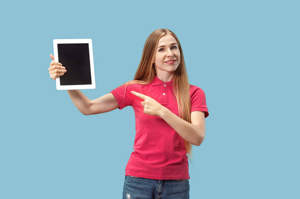 Portrait of a confident casual girl showing blank screen of laptop isolated over blue background - Foto, immagini