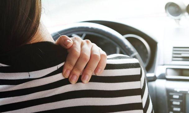 Close up woman having pain on neck and shoulder while driving car. Long driving on the way - Photo, Image