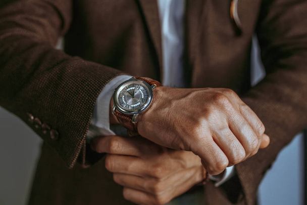 Man in suit fixing his cufflinks.Fashion portrait of young businessman handsome model man in casual cloth suit.Vintage smart casual outfit outdoor.Fashion model man posing in office.Suited man posing.closeup fashion image of luxury watch on wrist  - Фото, зображення
