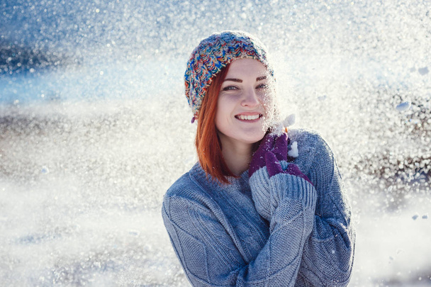 Winter portrait of young beautiful brunette woman wearing knitted snood covered in snow. Snowing winter beauty fashion concept. - Photo, Image
