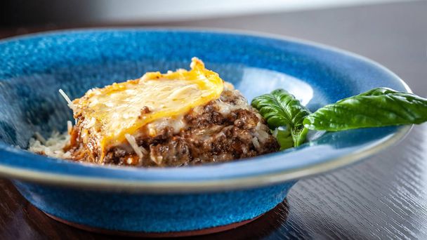 Italian lasagna with minced meat bolognese, carrots, and Parmesan cheese in a beautiful ceramic blue plate. Copy space, selective focus - Zdjęcie, obraz