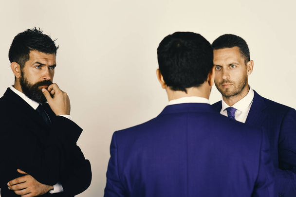 Men with beard and interested faces discuss business. Argument and business concept. CEOs settle disputes on light grey background. - Photo, Image