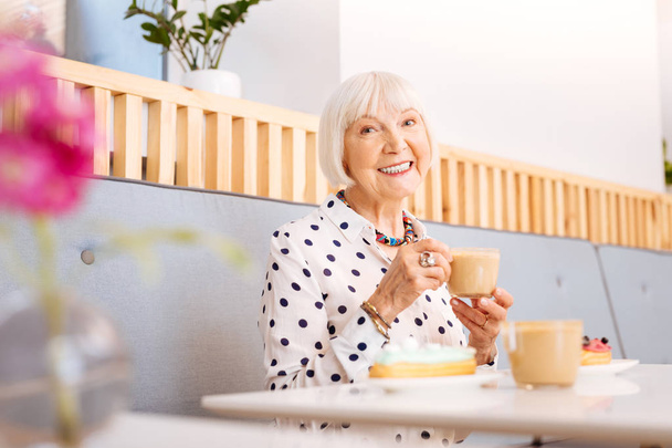 Positive senior woman relishing coffee - Zdjęcie, obraz