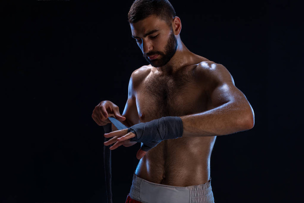 Spor boxer erkek el bilek tamamladı çeker. Siyah arka plan üzerine izole oryantal erkek modeli. - Fotoğraf, Görsel