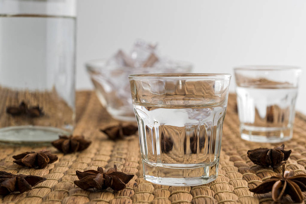 Gläser und Flasche traditionelles Getränk Ouzo oder Raki mit Anissternen auf natürlichen Matten - Foto, Bild