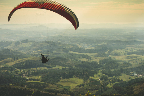 Paraglider vliegen op het mooie zonnige hemel over de groene bergen in Poos de Caldas, Minas Gerais - Foto, afbeelding