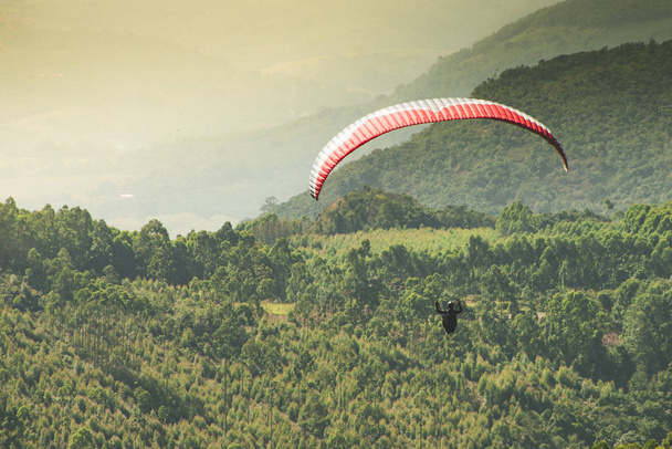 Paraglider flying on the beautiful sunny sky over the green mountains in Poos de Caldas, Minas Gerais - Foto, imagen