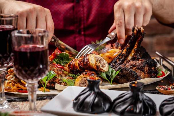 Traditional Georgian and Armenian cuisine. A man holds a knife and a fork in his hands, and there is meat cooked on a grill in a Georgian restaurant. Copy space, selective focus - Φωτογραφία, εικόνα