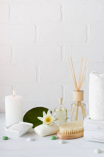 Spa setting and health care items, body oil, soap, candles, towel with lilac flower - 写真・画像