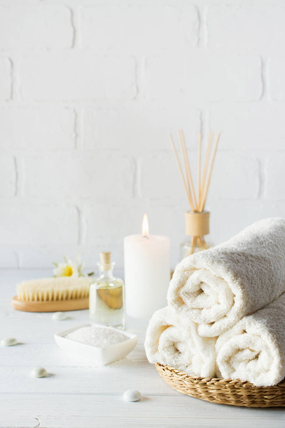 Fondo de aromaterapia SPA. Bodegón con toalla blanca, aceite de baño, cepillo de masaje y vela
. - Foto, Imagen