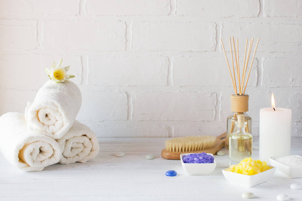 Спа-натюрморт с полотенцем, белой лилией, морской солью, маслом для ванны, сахарным скрабом для тела и свечами
  - Фото, изображение