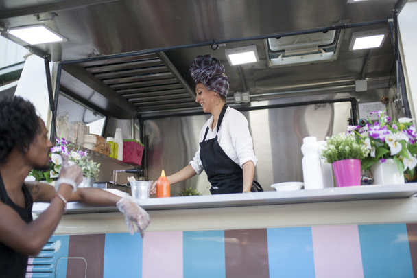 mooie en jonge vrouw die werkt op een food truck - Foto, afbeelding