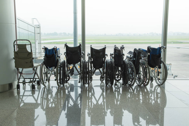 Wózek inwalidzki przez szybę w tle lotnisko Taxi runway sposób i góry. - Zdjęcie, obraz