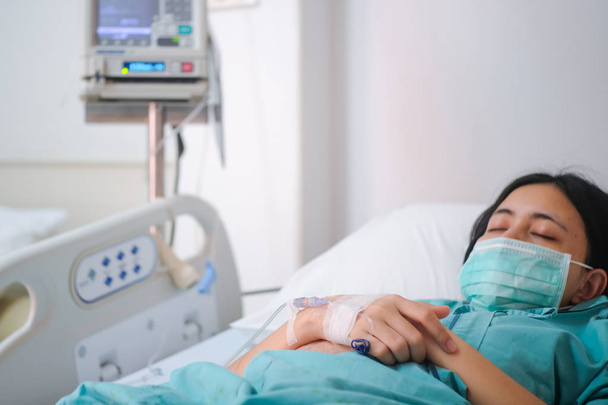 Acercamiento paciente joven acostada en la cama en el hospital con solución salina intravenosa normal
 - Foto, Imagen