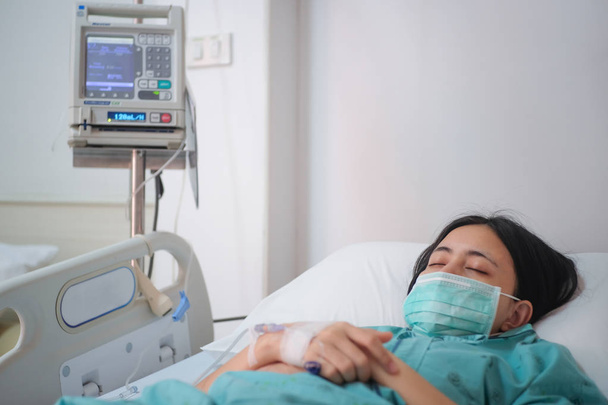 Acercamiento paciente joven acostada en la cama en el hospital con solución salina intravenosa normal
 - Foto, imagen