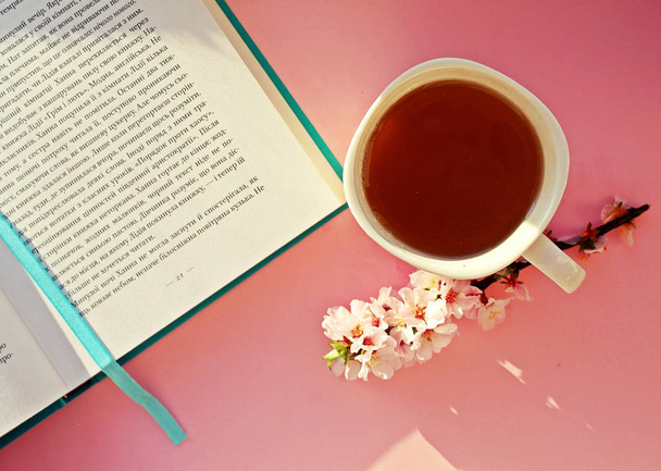 Green herbal tea next to an interesting book on the window sill flatlay  - Photo, Image