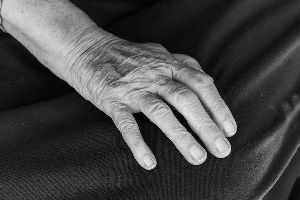 Een hand van een oude vrouw op haar schoot - zwart-wit - Foto, afbeelding