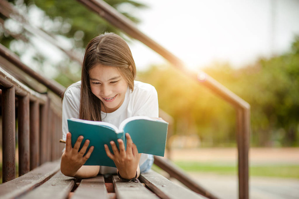 Gyönyörű, fiatal barna nő fekszik az amfiteátrumban egy könyvvel a kezében. Romantikus szabadtéri koncepció. - Fotó, kép