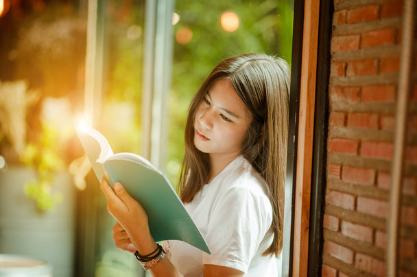 Giovane donna in un ristorante che legge un libro. giovane donna a casa seduta vicino alla finestra rilassarsi nel suo soggiorno libro di lettura
 . - Foto, immagini