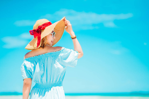 summer holidays, vacation, travel and people concept - smiling young woman in sun hat on beach over sea and blue sky background.copy space - Foto, Imagem