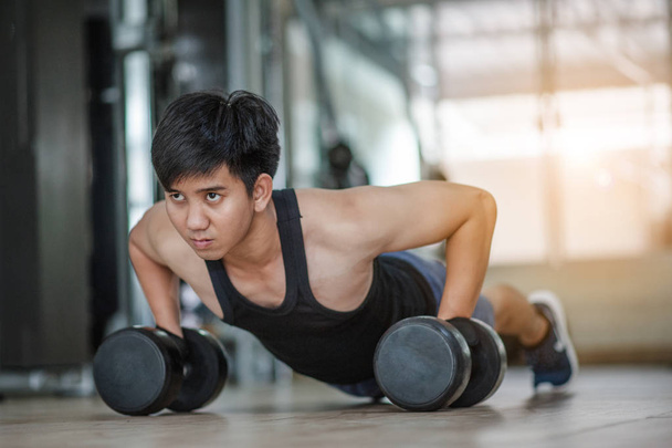 Sport. Handsome man doing push ups exercise with one hand in fitness gym.Fitness instructor at the gym - Control your mind, conquer your body.Handsome muscular man is working out with dumbbells in gym - Фото, зображення