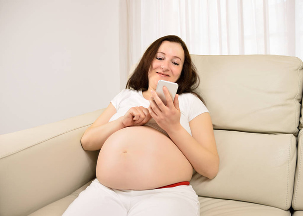 Pregnant woman texting with a smart phone - Foto, Imagem