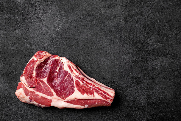 Meat raw steak lies on a black background. side view, copy space, top view - Foto, Imagen