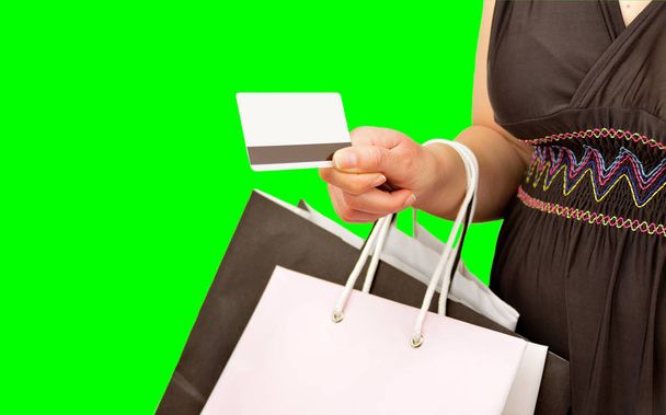 woman holding the shopping bags with credit card in hand, isolated cutout on green background with chroma key.Concept of a shopaholic - Фото, зображення