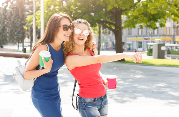 Happy girls with take away coffee outdoors - 写真・画像