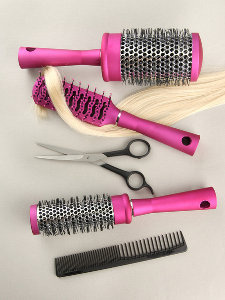 Escovas de pente, cabelo e tesouras de corte, sobre fundo cinzento
 - Foto, Imagem