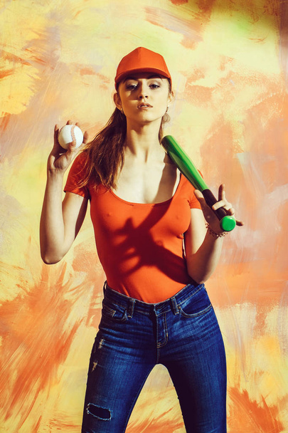 Pretty girl in red cap with green bat and ball - 写真・画像