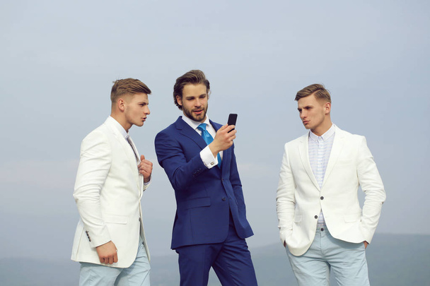 businessman with mobile or cell phone speaking with twin men - Foto, Bild