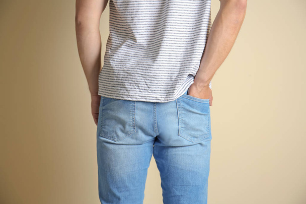 Mladý muž v stylové džíny na světlé pozadí - Fotografie, Obrázek