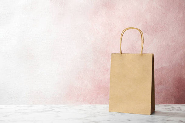 Mockup of paper shopping bag on table against color background - Fotografie, Obrázek