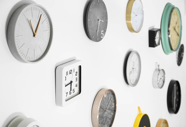 Many different clocks hanging on white wall. Time of day - Valokuva, kuva