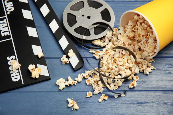 Composition with popcorn, film reel and clapperboard on wooden background - Fotoğraf, Görsel