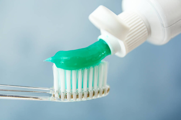 Squeezing toothpaste on brush against color background, closeup - Φωτογραφία, εικόνα