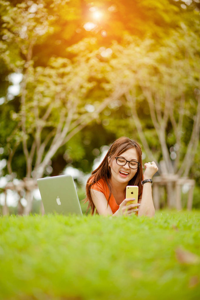 Fiatal, gyönyörű ázsiai nő dolgozik a szabadtéri parkban, boldog pihenést. tulajdonos üzleti nő dolgozik szabadtéri park.internet és technológia koncepció. - Fotó, kép