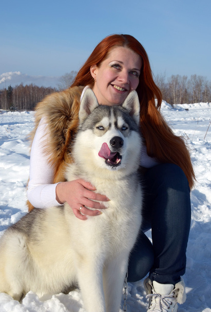 Retrato de una hermosa joven en invierno en la calle con un perro de raza husky
 - Foto, imagen