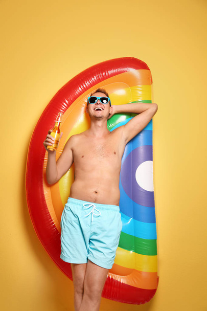 Shirtless man with inflatable mattress and bottle of drink on color background - Fotoğraf, Görsel