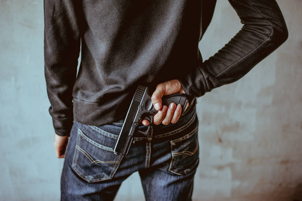 A man holding a gun on his back - Foto, Imagen