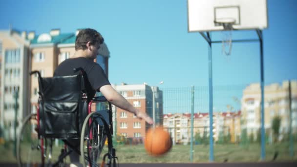 El hombre discapacitado juega baloncesto desde su silla de ruedas, al aire libre
 - Metraje, vídeo