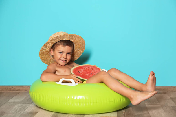 Cute little boy with inflatable ring and watermelon near color wall - Photo, image