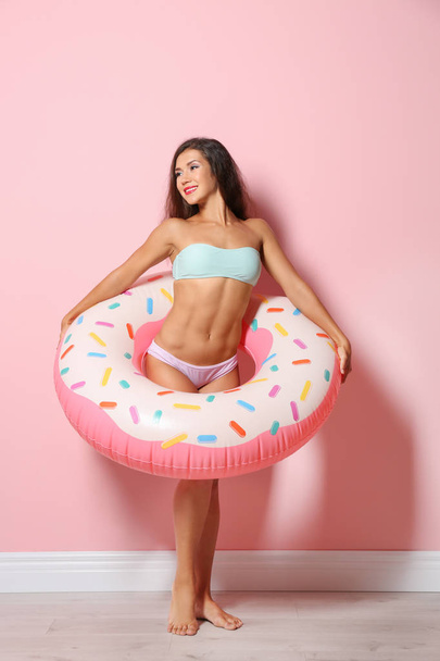 Beautiful young woman with inflatable ring near color wall - Fotoğraf, Görsel