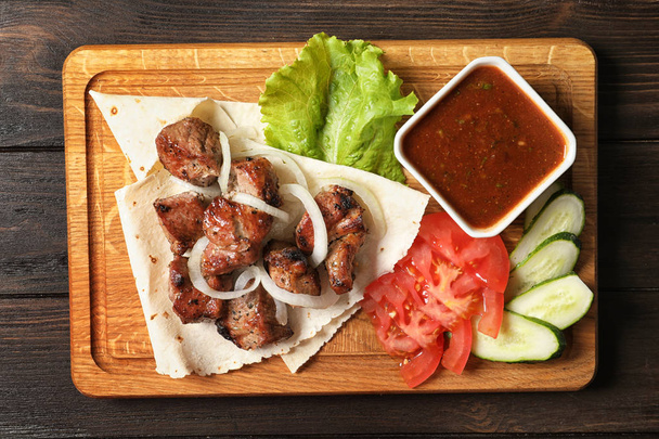 Wooden board with shish kebab and sauce on table, top view - Φωτογραφία, εικόνα
