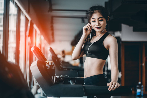 Portrait of Fitness woman running on treadmill in gym listening to music.exercising concept.fitness and healthy lifestyle. - Photo, Image
